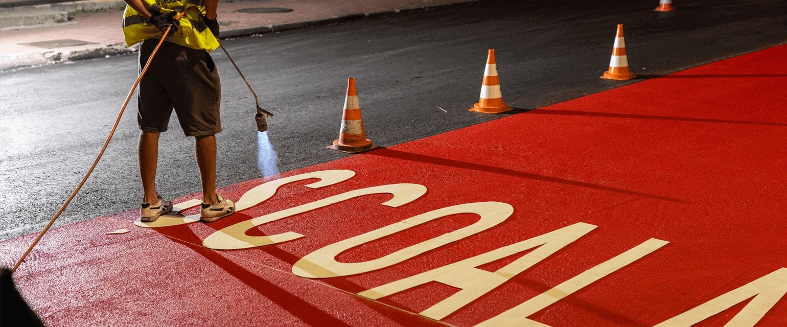 Safe Roads project crew member fixing a crossing at night, close look at the word Scoala on the road